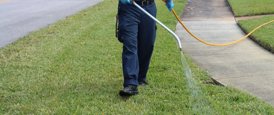 Worker in Florida spraying grass with a lawn care treatment.