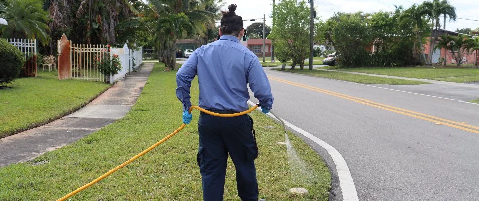 Crew spraying liquid lawn fertilizer on grass in Miramar, FL.