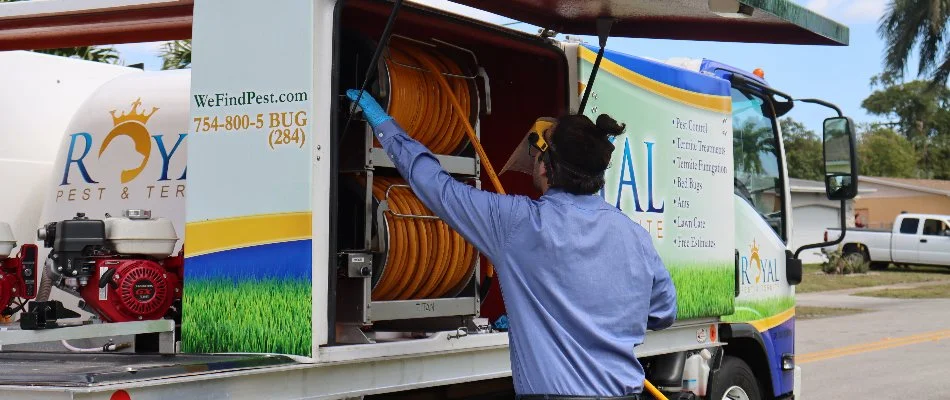 Pest control employee rolling up hose in Miramar, FL.