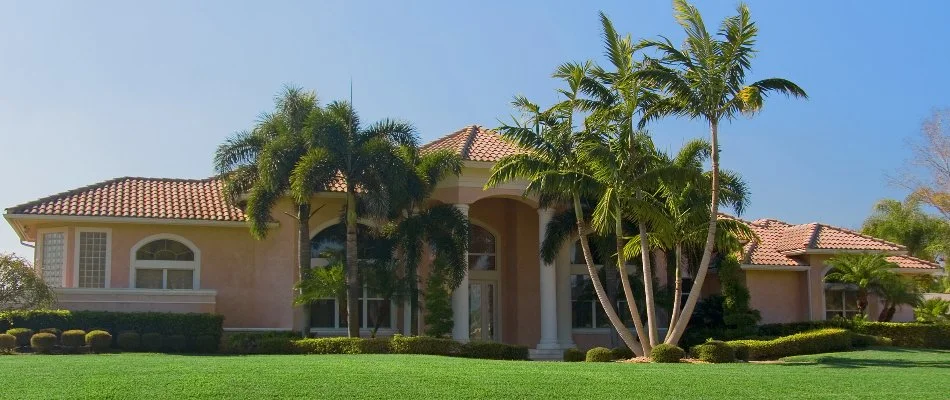 A home in Deerfield Beach, FL with palm trees and green grass.