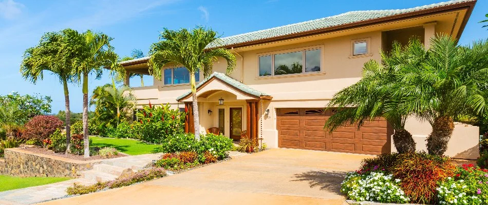 A home in Dania Beach, FL, with palm trees and other various plants.