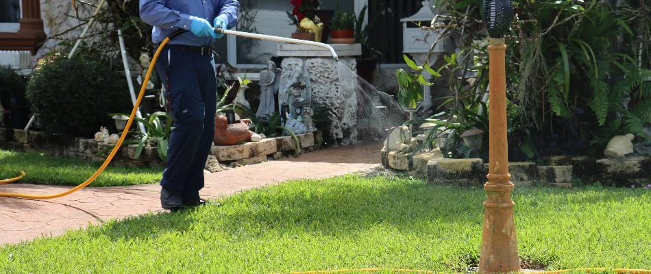 A pest control professional applying a treatment to a lawn in Coral Springs, FL.