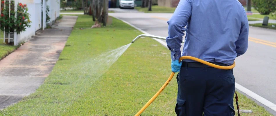 A lawn care professional in Hallandale Beach, FL spraying a lawn with liquid fertilizer.