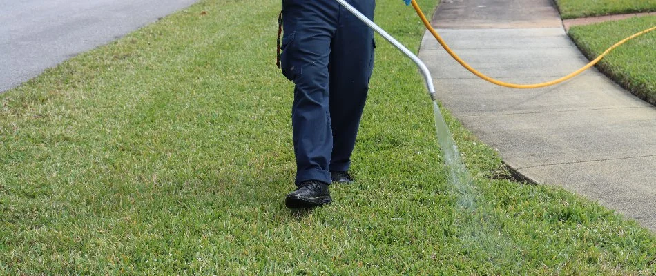 A lawn care professional spraying the grass on a property in Coconut Creek, FL.