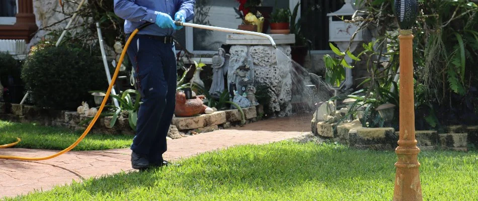 Tech spraying weed control treatment on grass in Miami Shores, FL.