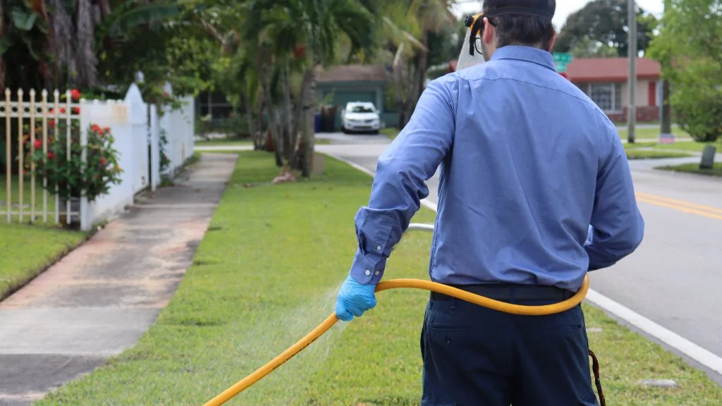 Employee applying fertilizer treatment to lawn.